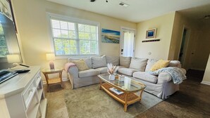 A living room with two sofas, a glass coffee table, a TV, and a lamp.