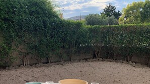 Taula blanca a l'aire lliure amb un bol, dues copes i dos tamborets.
