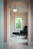 A narrow hallway with a window, a chair, and a small table.