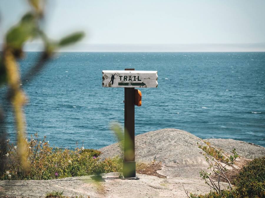 Un cartel indicador en la costa rocosa, con vista al mar.