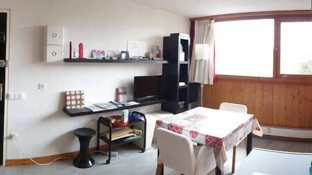 A small, well-lit room with a dining table, chairs, a black cabinet, and a window with curtains. - Studio 4 people Les Arcs 1600 (Bourg-Saint-Maurice)