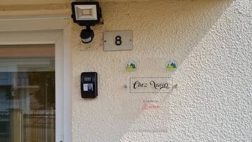 A textured wall with a house number '8', a security camera, a doorbell, and a sign reading 'Chez Xavier'.