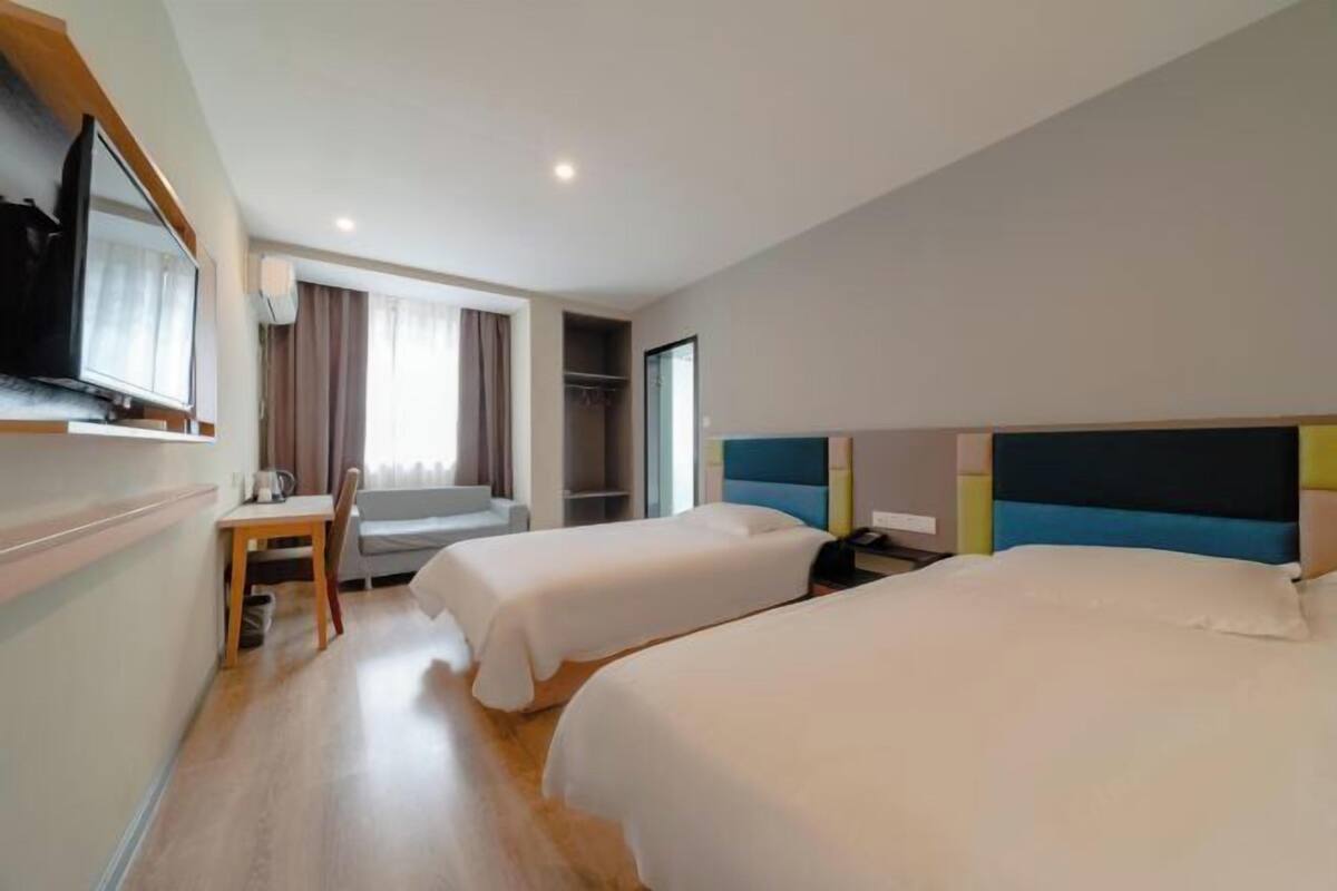 Ein Hotelzimmer mit zwei Betten, einem Schreibtisch, einem Stuhl, einem Fernseher und einem Kleiderschrank.