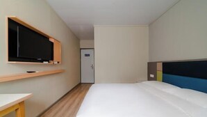 A hotel room with a bed, a television mounted on the wall, a small table, and a door in the background. - Home Inn Plus (Wuhan Chuhe Hanjie Metro Station Branch) (Wuhan)