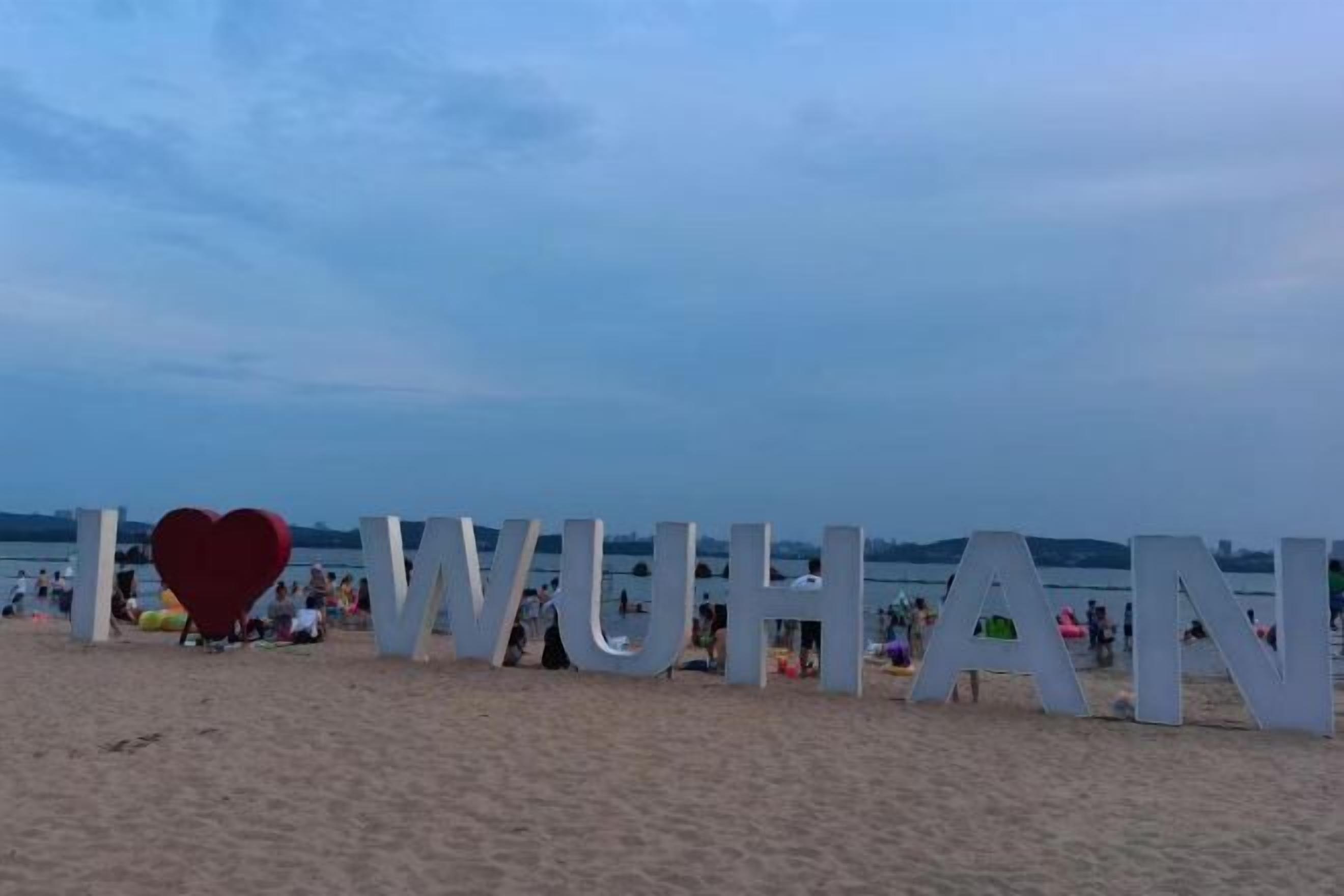 A beach with large white letters spelling "I ♥ WUHAN" and a red heart in the center.