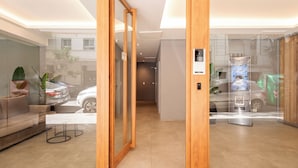Un hall d’h ôtel moderne avec un plancher en bois, un canapé, une table basse et une porte en verre donnant sur l’extérieur.