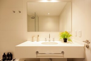 A bathroom with a large mirror, a sink, a shower, and a potted plant. - Live New & Modern ApartmentRecoleta B12 (Buenos Aires)