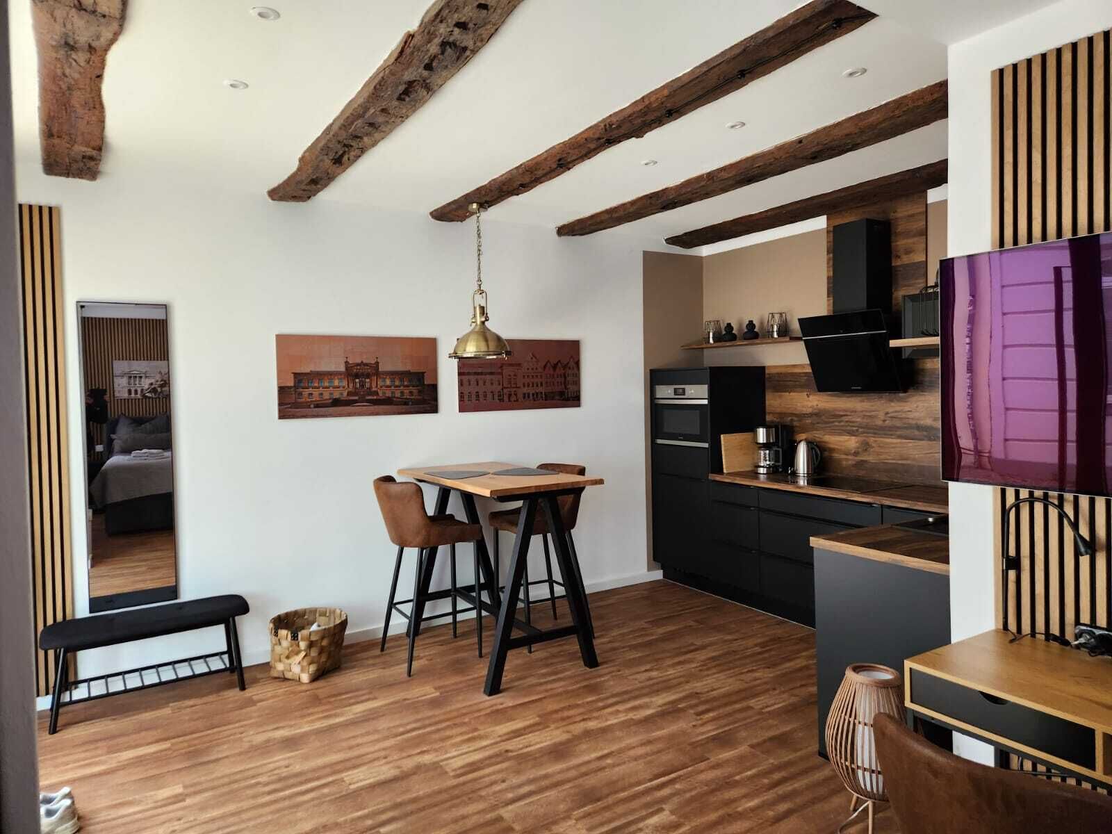 Eine moderne Küche mit Holzbalken, einem Essbereich mit einer Bank und einem an der Wand montierten Fernseher.