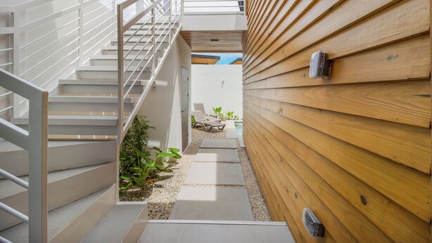 Eine moderne Treppe führt zu einem Holzdeck mit Sitzgelegenheit im Freien.