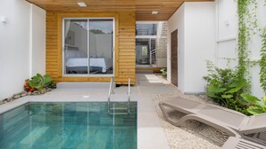 Ein moderner Poolbereich im Freien mit Holzterrasse, einer Glastür, die zu einem Schlafzimmer führt, und einer Treppe zu einer oberen Ebene.