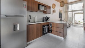 Eine moderne Küche mit Edelstahl-Kühlschrank, Holzschränken, integriertem Mikrowellenherd und einer Kaffeestation.
