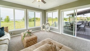 A spacious living room with large windows, a ceiling fan, and a view of a patio area. - Luxurious Lakefront Escape – Premier EAA Rental with Breathtaking Views (Winneconne)