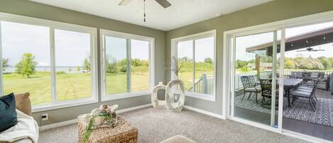 A spacious living room with large windows, a ceiling fan, and a view of a patio area.