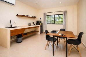 A compact kitchen with a built-in stove, a sink, and a dining area with a table and chairs. - Spacious Loft in Cancún with Large Bath & Full Kitchen (Cancún)