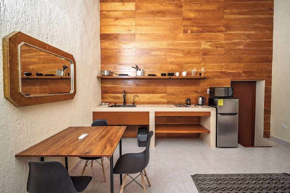 Una cocina compacta con salpicadero de madera, un microondas integrado y un refrigerador.