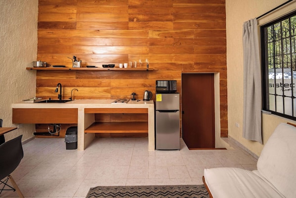 A compact kitchen with wooden paneling, a refrigerator, a microwave, and a sink. - Private 1-Bedroom Suite in Cancún with Living Area (Cancún)