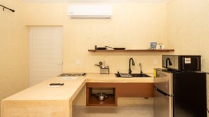 Eine kompakte Küche mit Einbauherd, Spüle, Mikrowelle und Kühlschrank.
