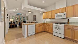 A spacious kitchen with wooden cabinets, a central island, and built-in appliances. - Sun Valley 3BR - Hot Tub - 5min to River Run - Premium Snow Star Complex (Ketchum)