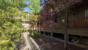 A building with a stone pathway, a wooden fence, and a tree with pink flowers. - Sun Valley 3BR - Hot Tub - 5min to River Run - Premium Snow Star Complex (Ketchum)