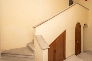 A staircase with a stone handrail, a wooden door, and a tiled floor.