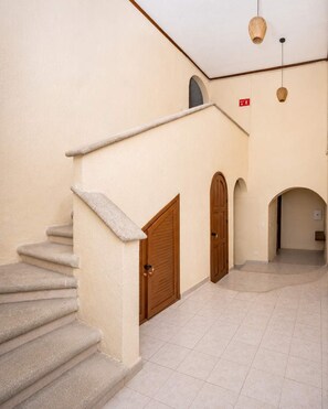 A staircase leading to a door, a tiled floor, and a hallway with an arched doorway.