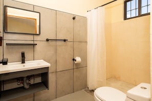 Ein Badezimmer mit Waschbecken, Spiegel, Toilette und Duschvorhang.