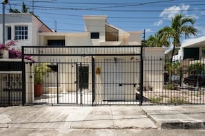 Il s’agit d’une propriété résidentielle fermée, avec une façade blanche, un garage et une allée bien visible.