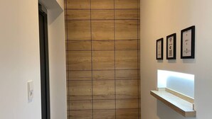 Un couloir avec un mur lambrissé en bois, une porte et une étagère où sont exposés des certificats encadrés.