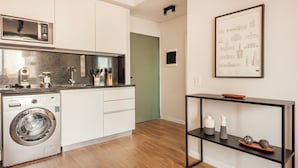 Una cocina moderna con armarios blancos, lavadora integrada y encimera negra.