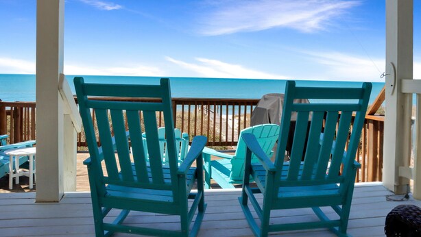 A covered deck with turquoise Adirondack chairs facing a beach. - Sailor's Dream (Port St. Joe)
