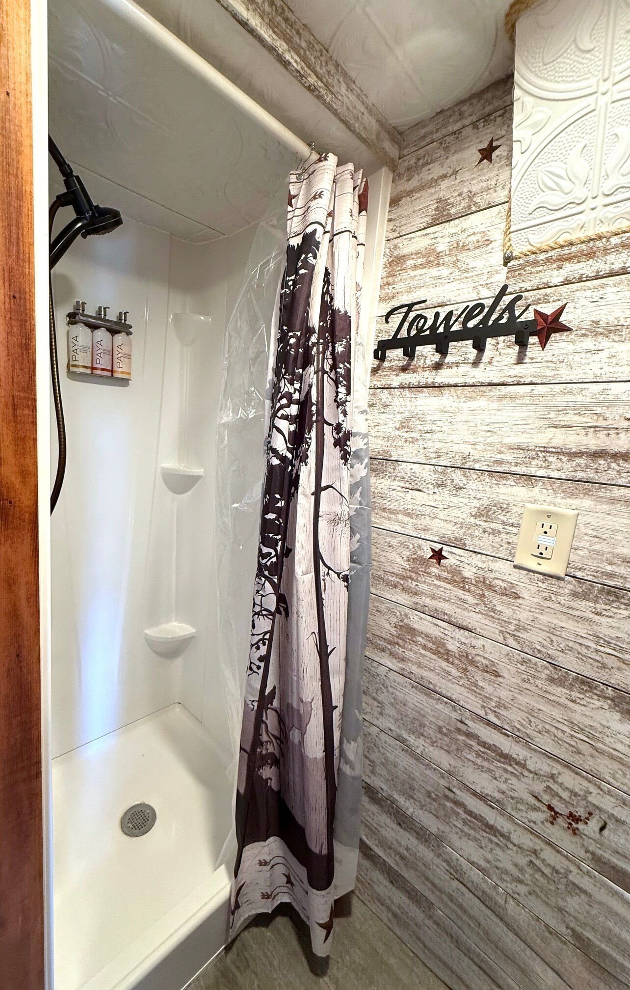 A bathroom with a shower curtain, a wall-mounted towel rack, and a decorative sign.