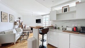 A modern kitchen with white cabinetry, a wooden countertop, and a bar stool. - Paris 8 Madeleine beauty (Paris)