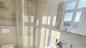 A modern bathroom with a glass-enclosed shower, a white sink, and a toilet. - Paris 8 Madeleine beauty (Paris)