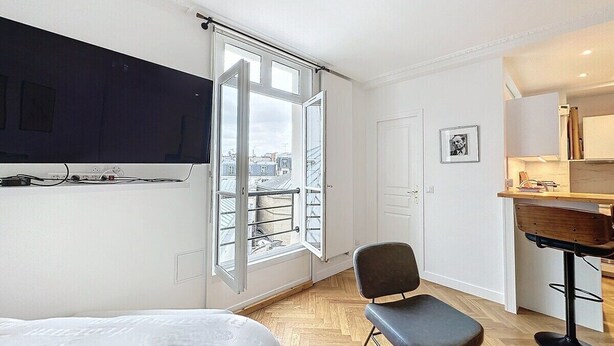 A bedroom with a bed, a chair, a desk, a window with a view of buildings, and a door. - Paris 8 Madeleine beauty (Paris)