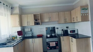 A kitchen with wooden cabinets, a stove, a microwave, and a sink.