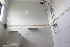 A small, tiled bathroom with a shower, toilet, and a shelf. - Cozy Spacious Home to relax with your family and friends (Nakuru)