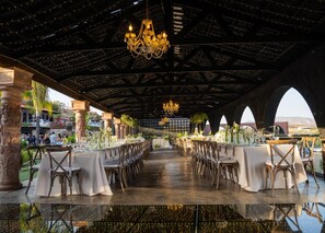 An indoor venue with a long table set for dining, chandeliers, and a view of the outdoors. - Finca Selah (Valle de Guadalupe)