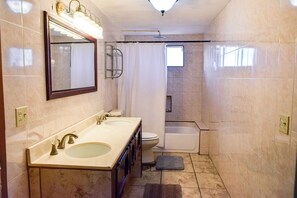 A bathroom with a double sink, a toilet, a shower, and a mirror.