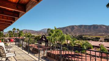 A balcony with a view of mountains, a grill, and outdoor seating.