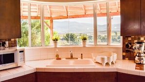 A kitchen with a large window, a sink, a microwave, and a blender. - Finca Selah (Valle de Guadalupe)