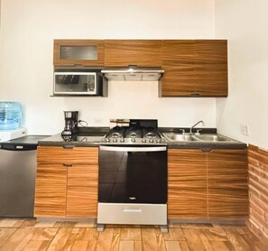 A compact kitchen with a stove, microwave, and sink. - Finca Selah (Valle de Guadalupe)