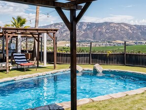A backyard with a swimming pool, a wooden pergola, and a view of mountains. - Finca Selah (Valle de Guadalupe)