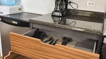 Een keuken met een ingebouwde vaatwasser, een koffiezetapparaat en een lade met keukengerei.
