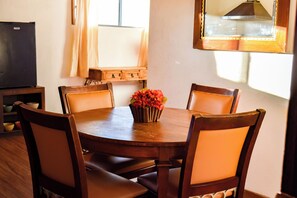 Une table à manger avec six chaises, un vase rempli de fleurs et un buffet en bois avec des tiroirs.