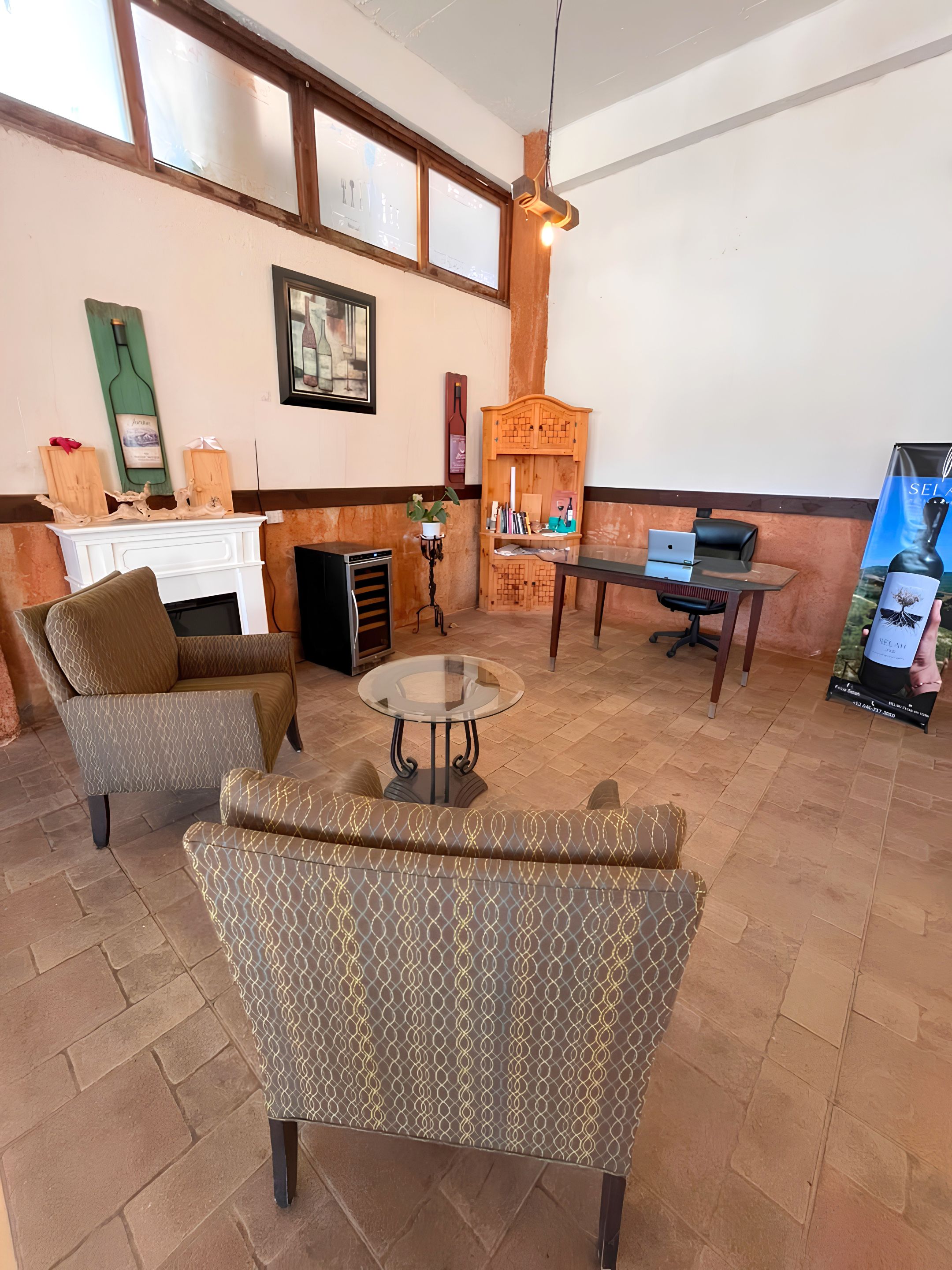 A room with a fireplace, seating area, and a desk with a laptop.