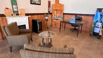 A room with a fireplace, seating area, and a desk with a laptop.