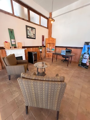 A room with a fireplace, seating area, and a desk with a laptop.