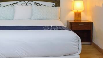 Una cama bien tendida con un cabecero de madera y una mesita de noche con una lámpara.