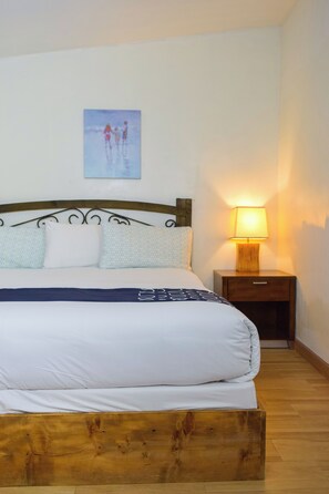 A neatly made bed with a wooden headboard and a bedside table with a lamp.