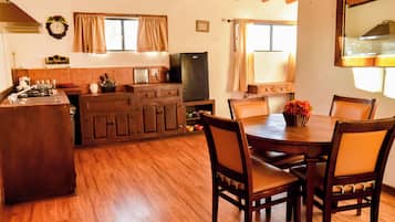 Una cocina con armarios de madera, una mesa de comedor con sillas y un televisor.
